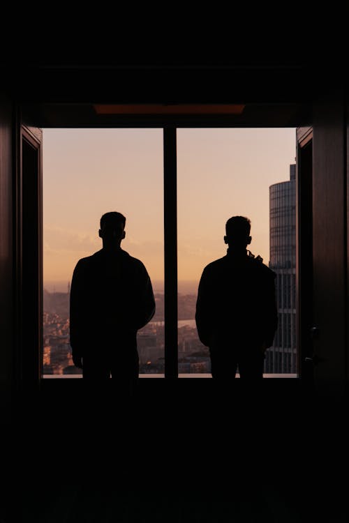 Free Silhouettes of Men Standing by the Window in a High Floor Apartment Stock Photo