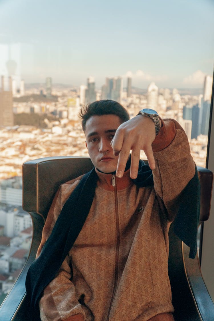 Young Man Sitting In An Armchair In A Modern Apartment With The View Of The City