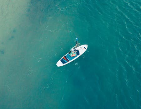 Explore the beauty of Playa del Carmen with this aerial shot of a woman kayaking on clear, turquoise waters.