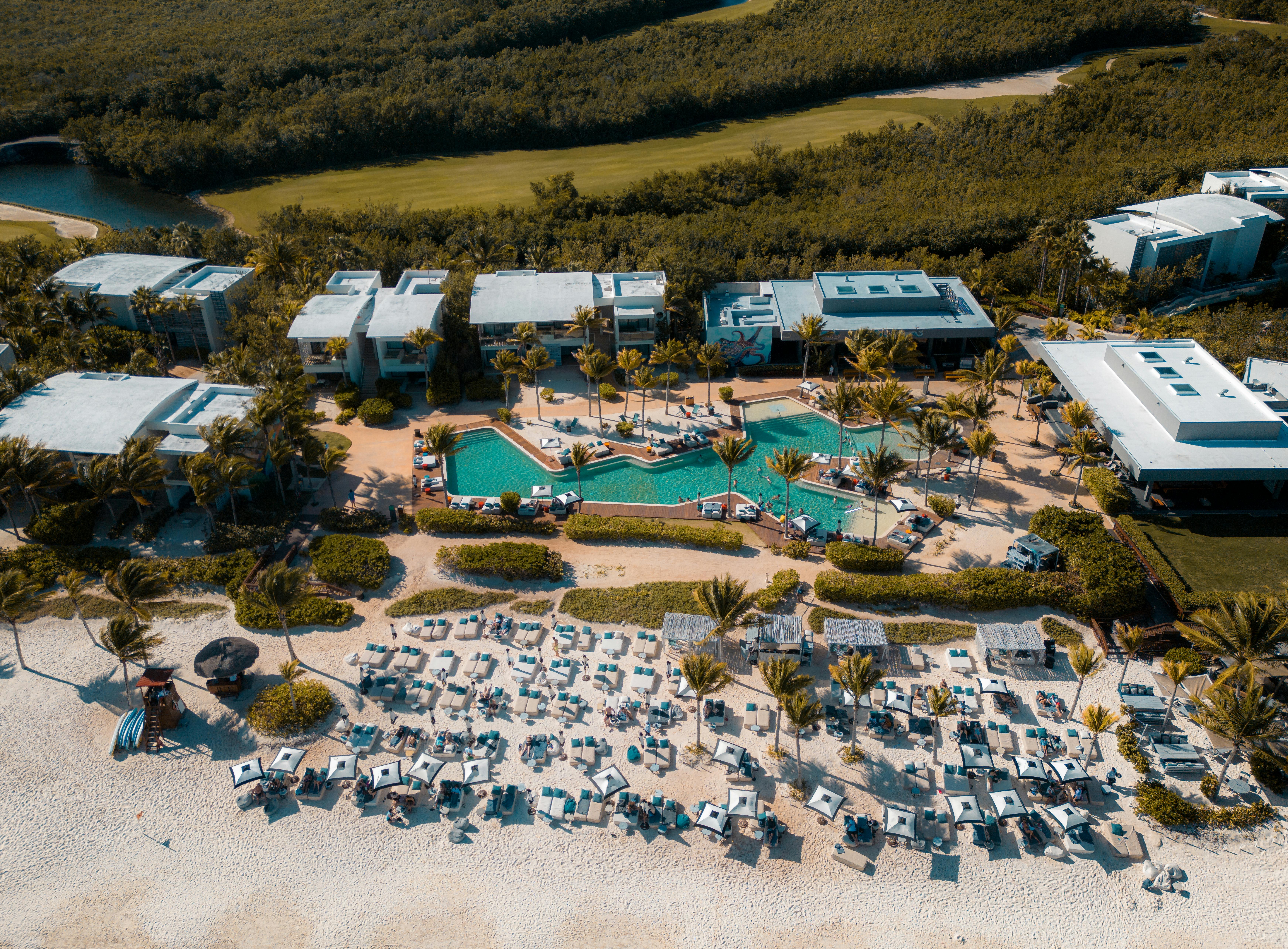 what to pack for a riviera maya tour - A stunning aerial view of a luxury resort in Playa del Carmen, featuring a large swimming pool and beachside lounging area.
