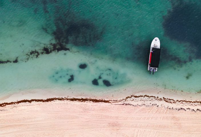 A serene aerial view of a boat by the shore in Playa del Carmen, Mexico.