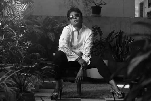 Woman in Sunglasses and High Heels Sitting between Plants 
