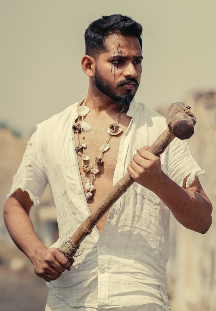 Man Wearing Seashell Necklace Holding Mallet