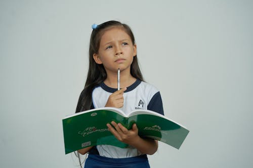 Niña Estudiante Pensando Y Sostiene Cuaderno