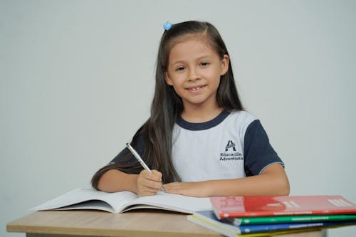 Studying Little Girl Sitting at a Desk with Textbooks