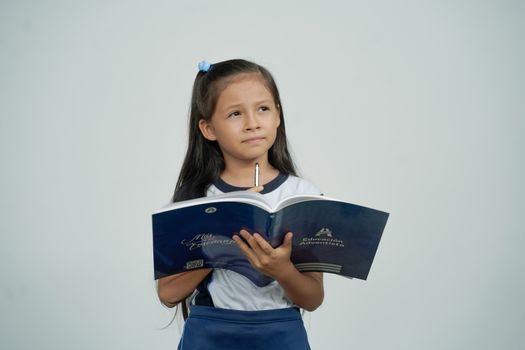 Niña estudiante pensando y sotiene un cuaderno