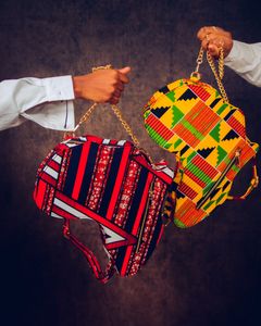 Colorful handbags with African patterns presented by two hands in a stylish art shot.