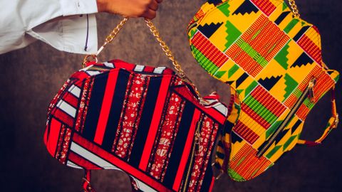 Colorful handbags with African patterns presented by two hands in a stylish art shot.