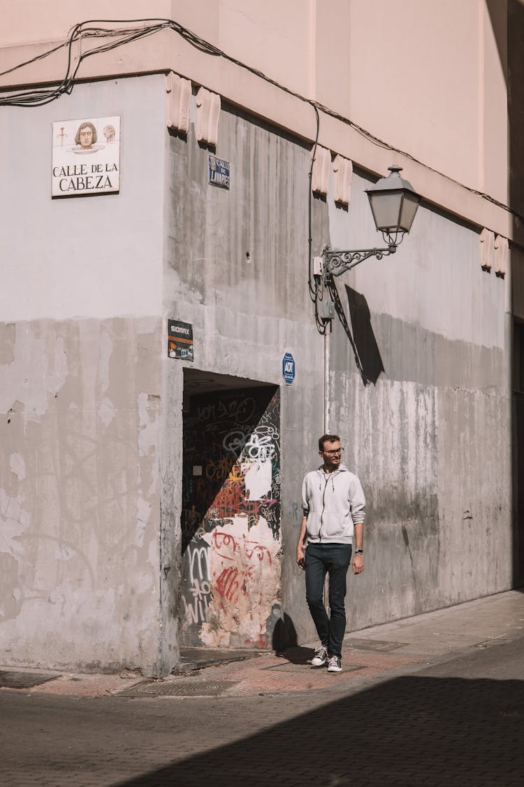 Man Walking Near Stone Building On City Street