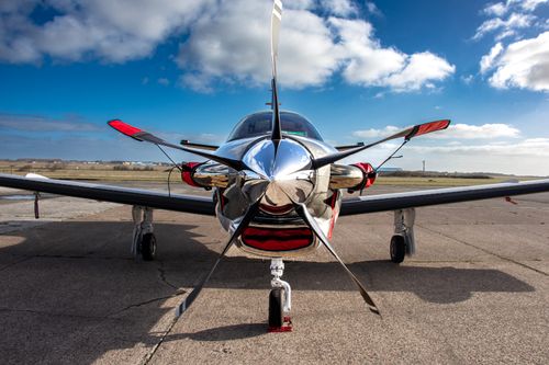 Free Close-up view of a shiny propeller airplane on a tarmac under a bright blue sky with lush clouds. Stock Photo