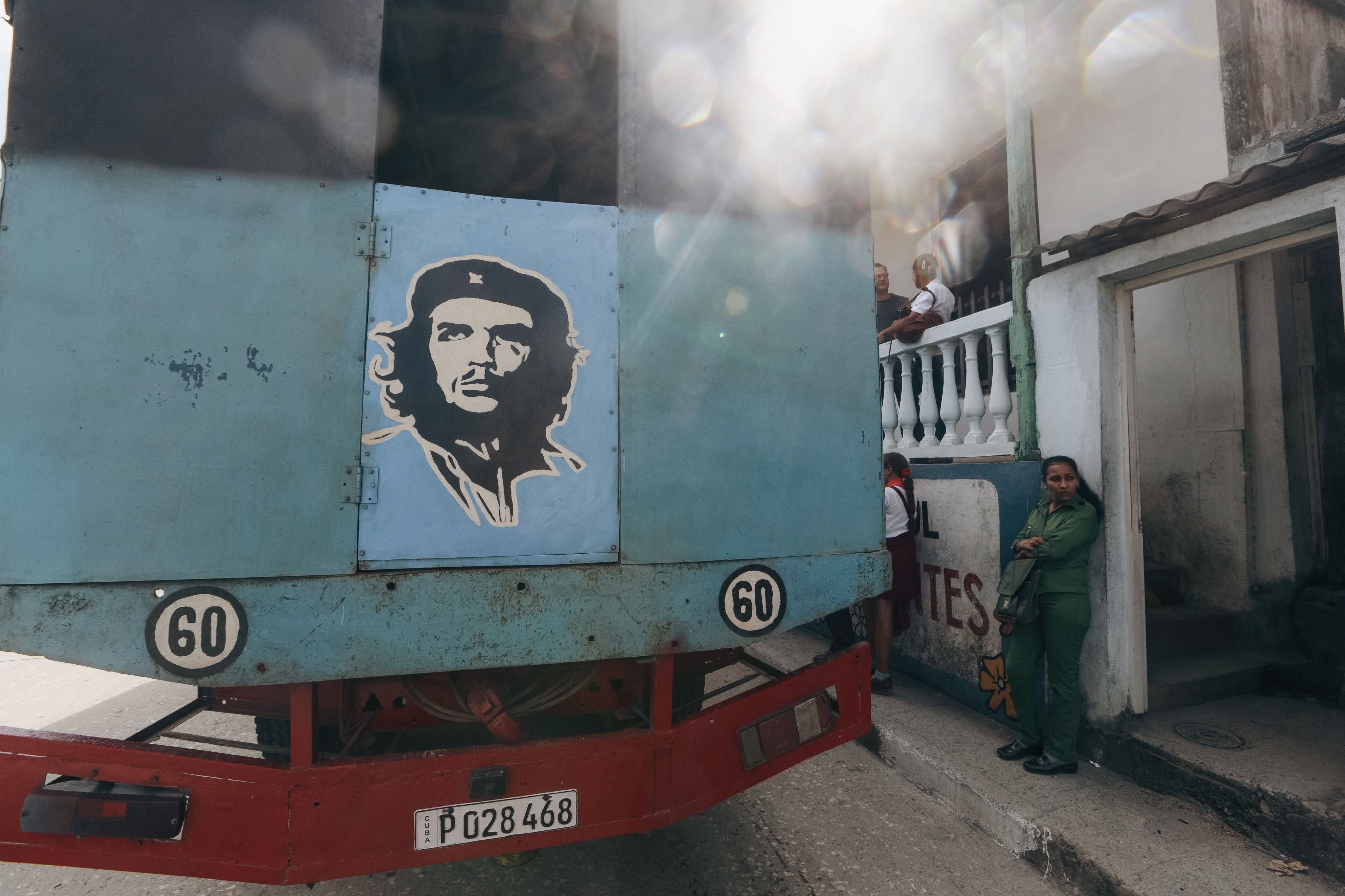 A vibrant urban scene featuring a truck with a mural of Che Guevara and local people.