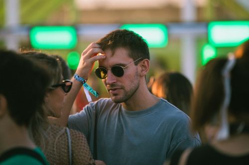 Free Man wearing sunglasses at a lively outdoor festival during daylight. Stock Photo