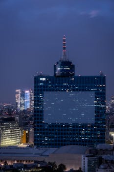 Illuminated skyline of Mexico City featuring tall skyscrapers against a night sky.