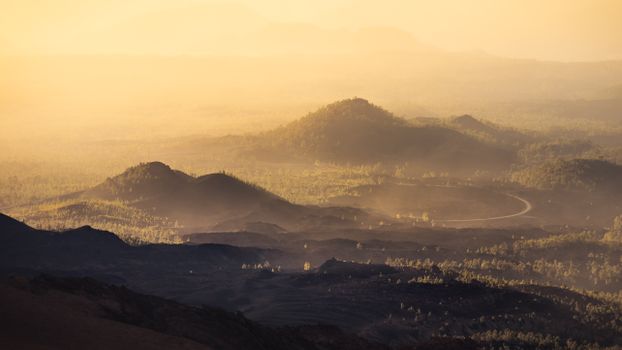 Majestic view of Tenerife's volcanic landscape at sunset with misty hills.