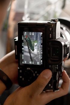 Close-up of photographer adjusting settings on a digital camera indoors, focusing through viewfinder.