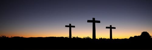 бесплатная Пейзажный вид на 3 креста, стоящих во время заката Стоковое фото