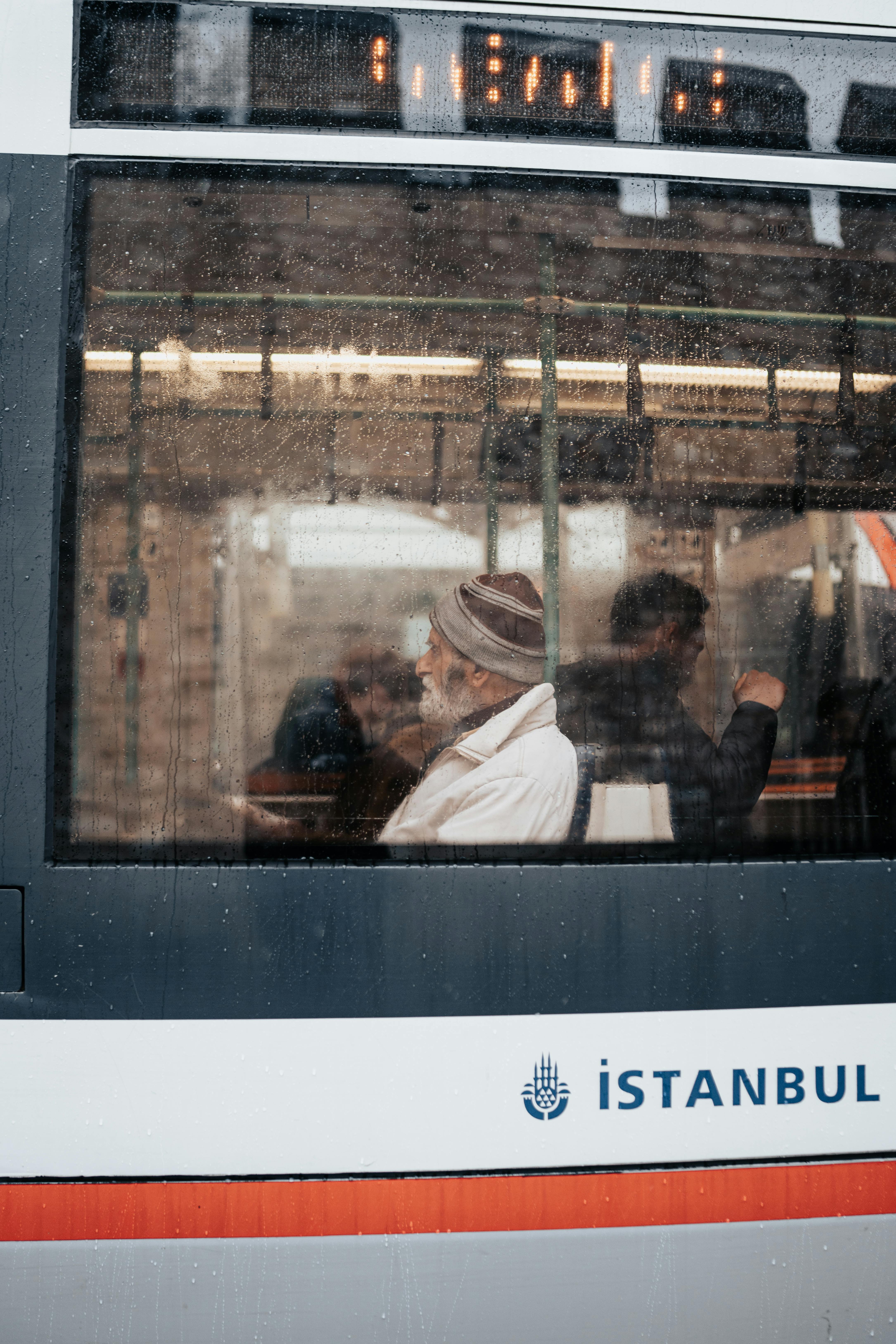 An elderly man seen through a rainy tram window in Istanbul, capturing a moment of daily urban transit.