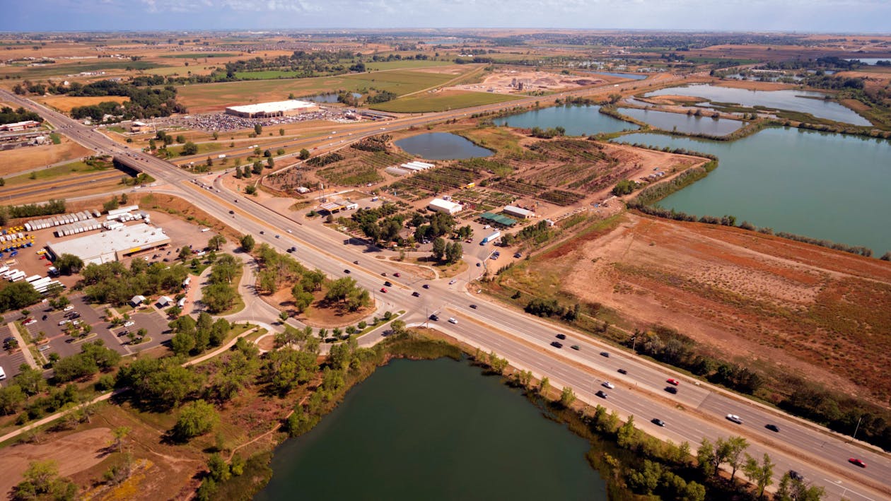 Aerial Photography of an Open Road With Cars Near City and Lake during Daytime