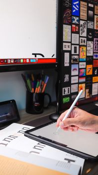 Close-up of a hand using a stylus on a tablet in a modern digital workspace.
