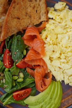 Delicious nutritious breakfast of smoked salmon, avocado, eggs, salad, and toast.