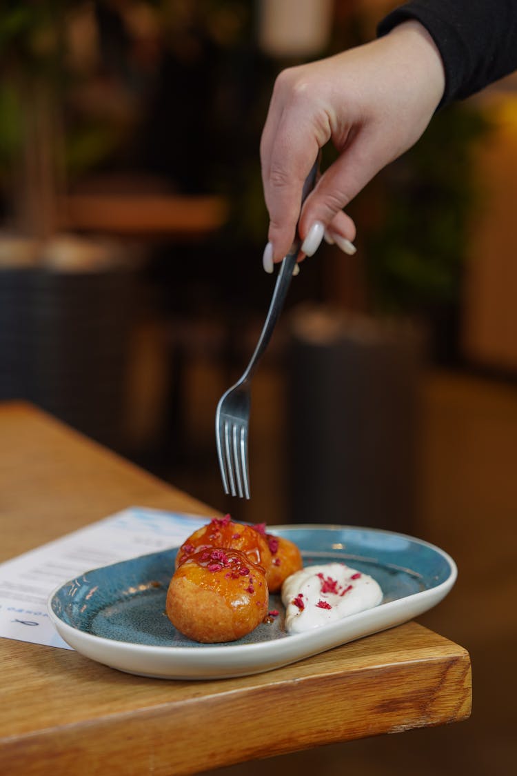 Hand Holding A Fork Over Of A Dessert