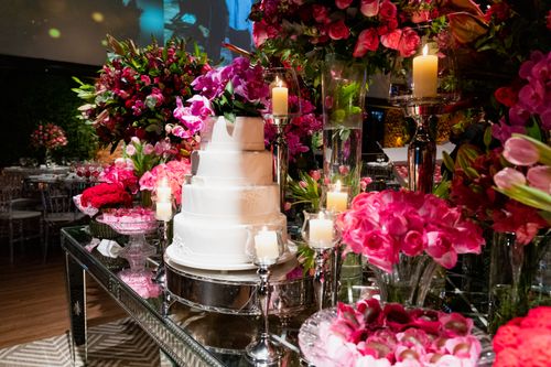 Free A beautifully decorated wedding reception table with a tiered cake and vibrant floral arrangements. Stock Photo