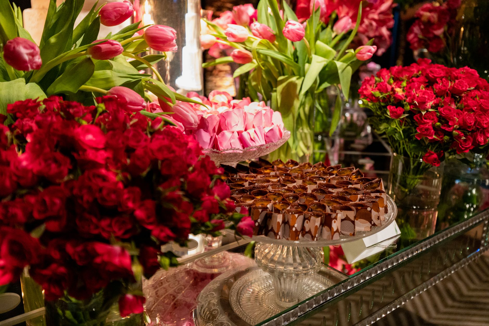 Luxurious floral arrangements with chocolates and sweets adorn a table at a wedding reception.