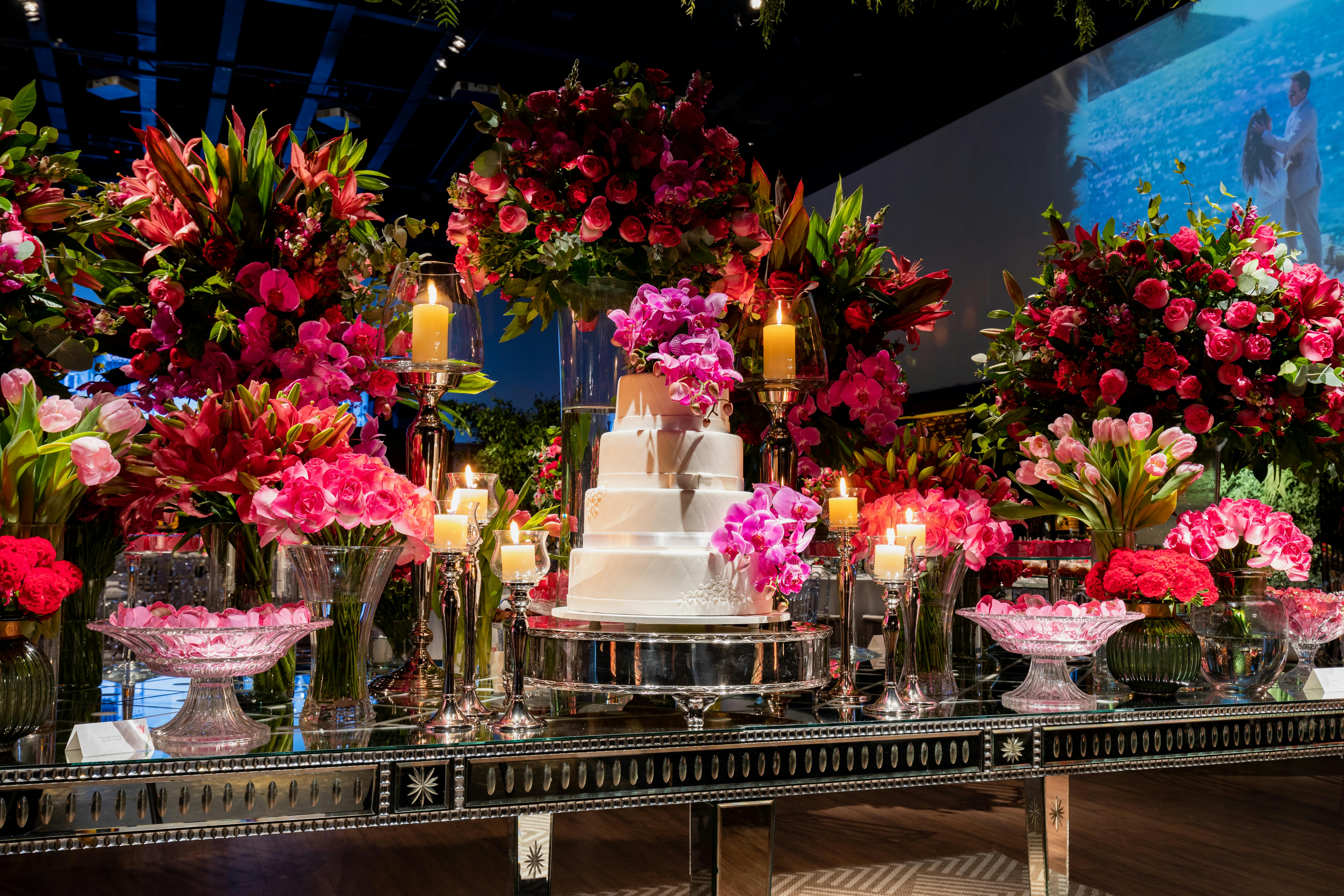 A beautifully decorated wedding table with a tiered cake and vibrant floral arrangements.