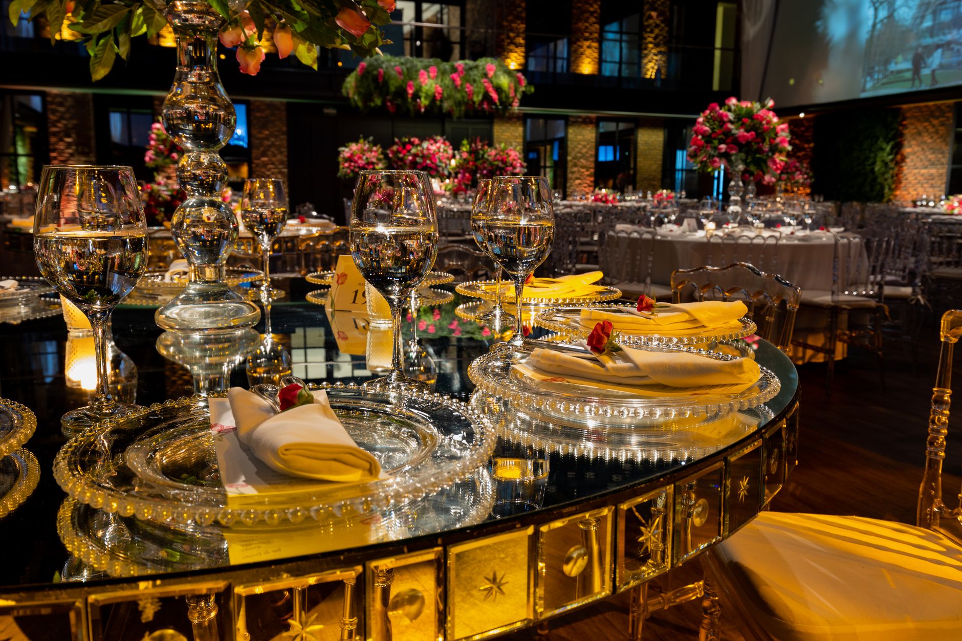 Sophisticated wedding reception setup featuring sparkling glassware and floral decor in a dimly lit venue.