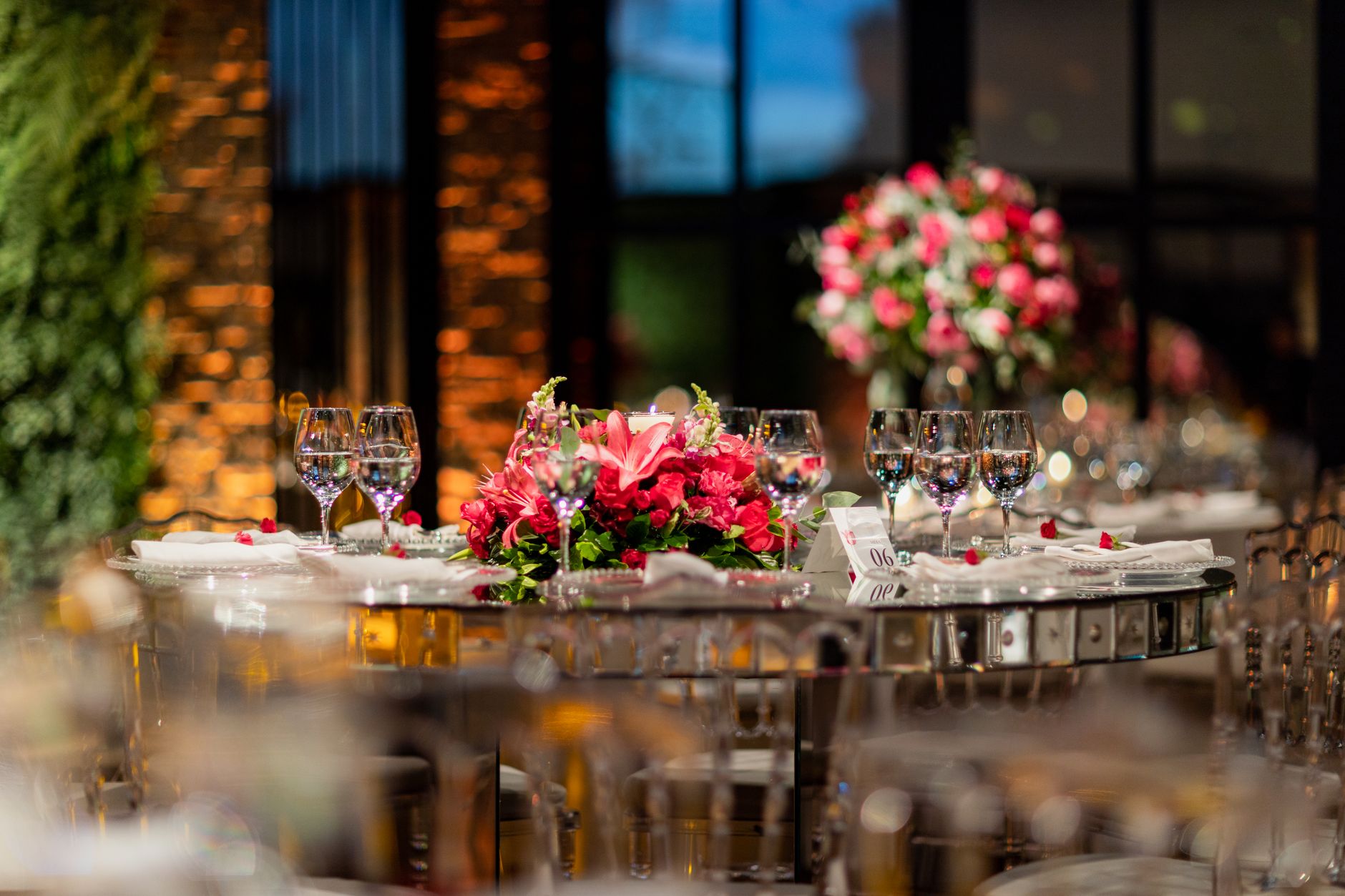 Luxurious dining setup with pink floral arrangements and glassware at an elegant wedding reception.
