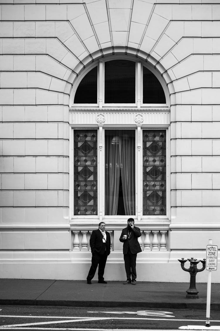 Two People Standing On A Sidewalk 