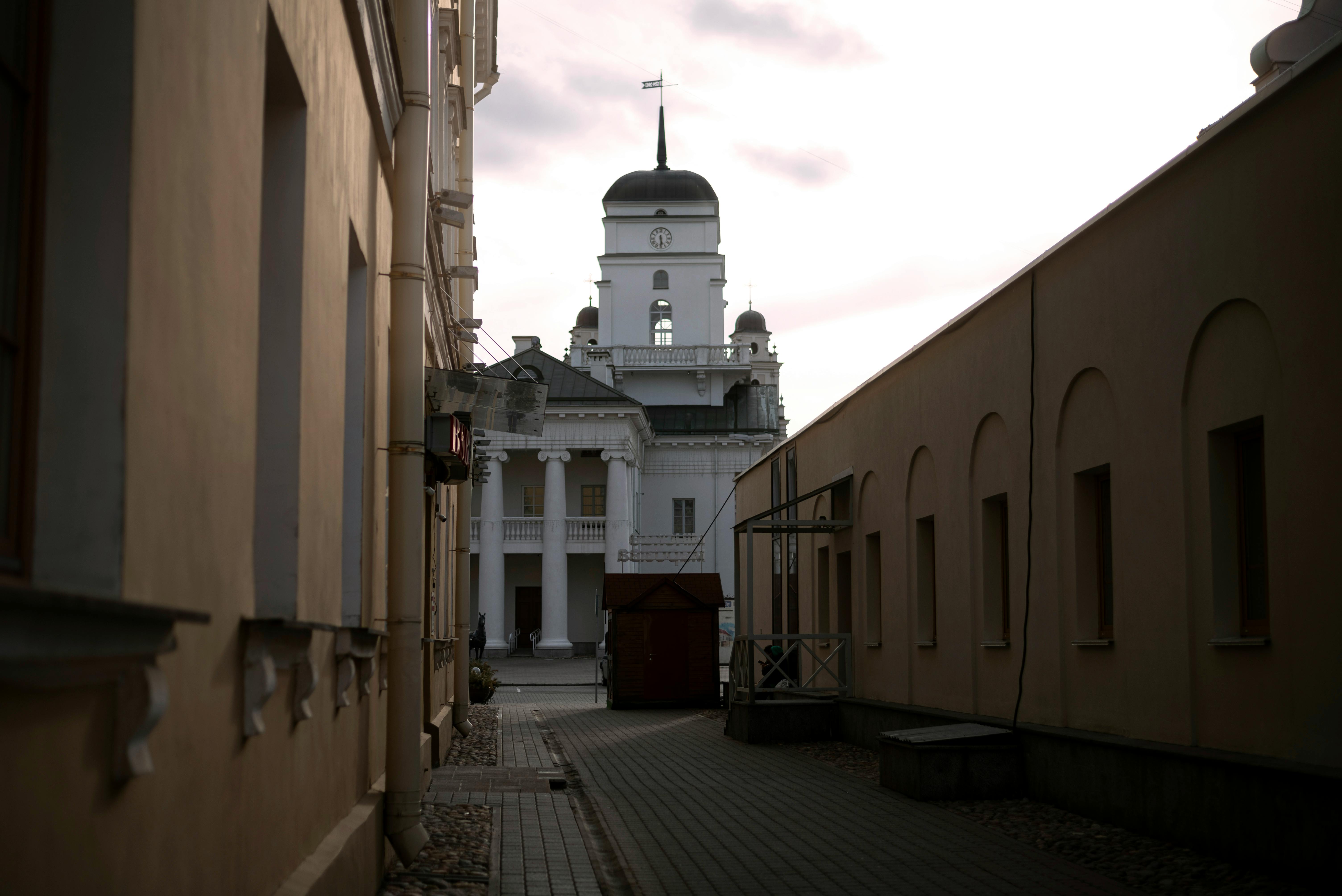 A picturesque view of a historic building seen from an urban alley at twilight, featuring architectural columns.