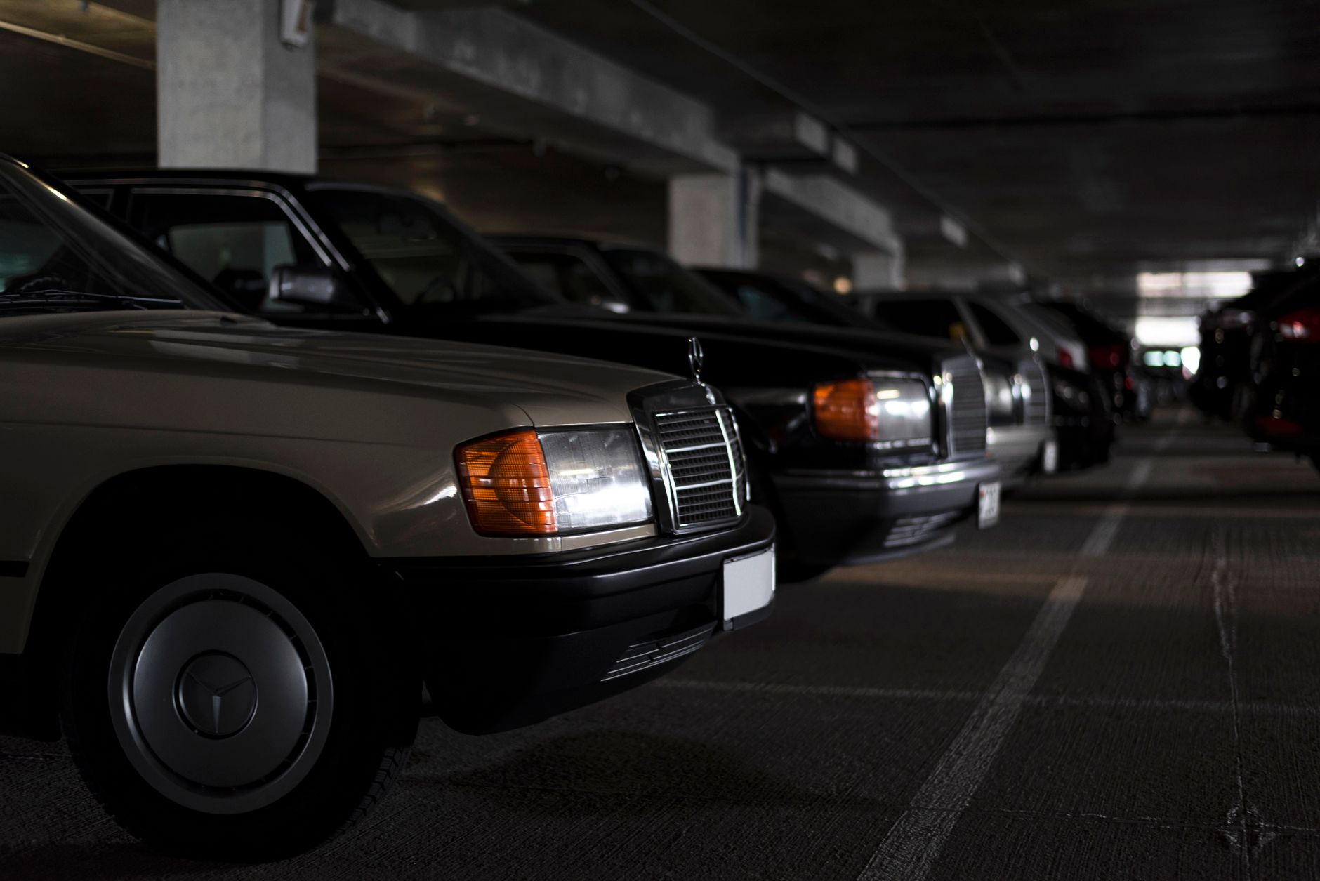 Classic Mercedes vehicles parked in a shadowy indoor car park, capturing a vintage feel.