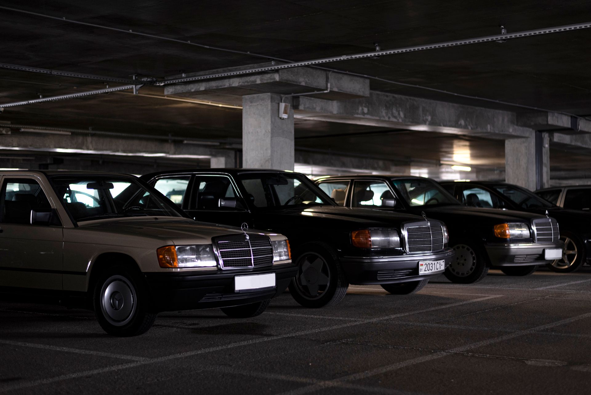 Collection of vintage Mercedes cars parked in a dimly lit indoor parking garage, showcasing classic automotive design.