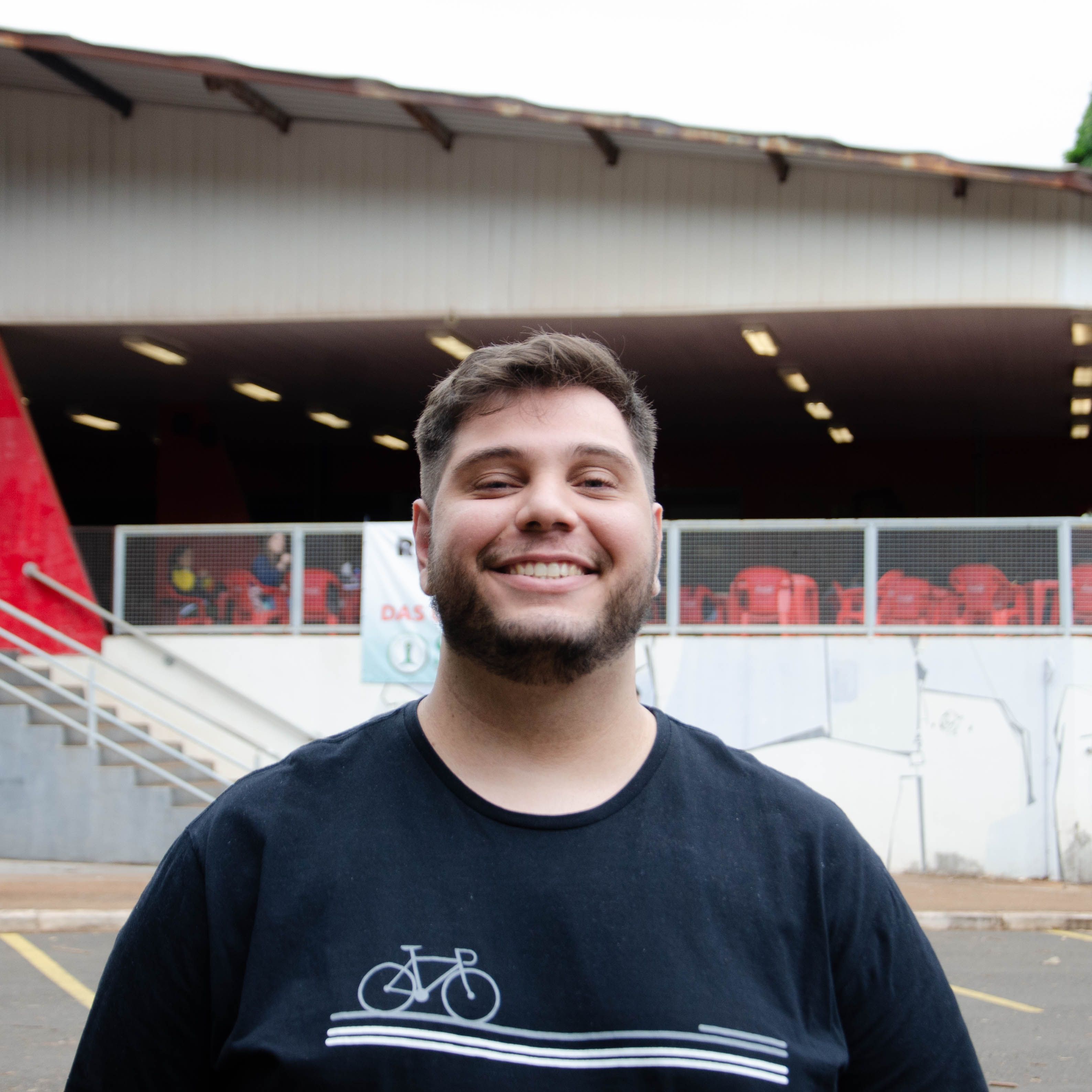 A young man smiles standing confidently outside a modern building.