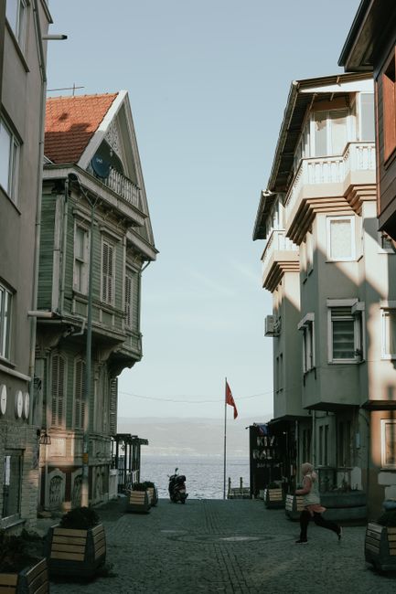 A quaint coastal street view showcasing historical architecture and a glimpse of the sea beyond.
