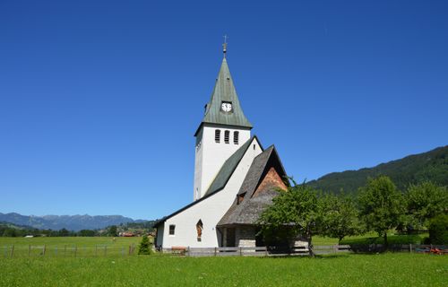 Free Picturesque rural church in green landscape under blue skies, embodying serene tranquility. Stock Photo