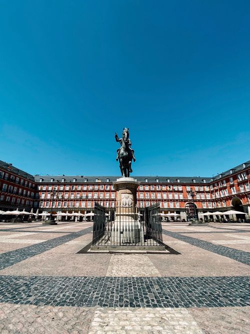 Free Sunlit view of Plaza Mayor in Madrid featuring iconic equestrian statue. A must-visit Spanish landmark. Stock Photo