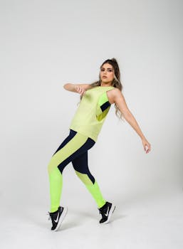 A woman in neon sportswear striking a dynamic pose against a white studio background.