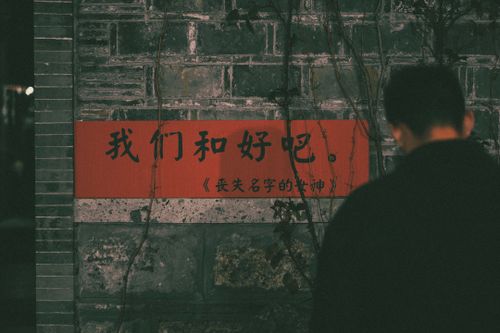 Free Man standing near a brick wall with Chinese sign at night, creating an urban mood. Stock Photo