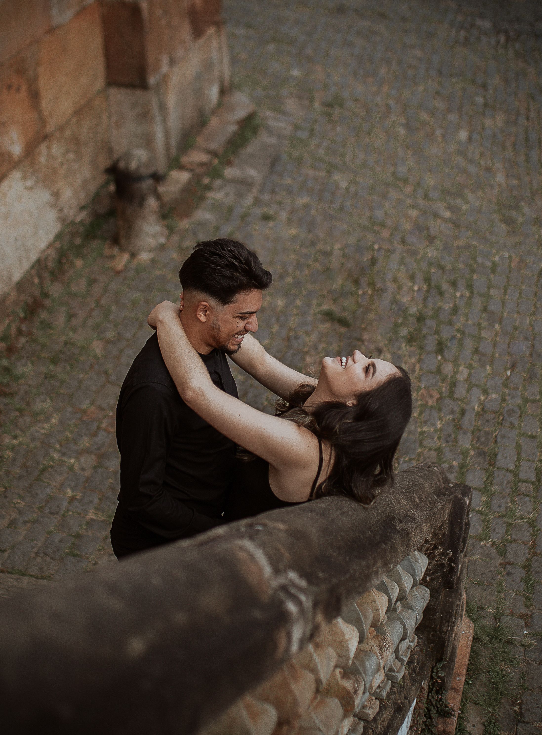 Joyful young couple embracing outdoors on a cobbled street, captured from above.