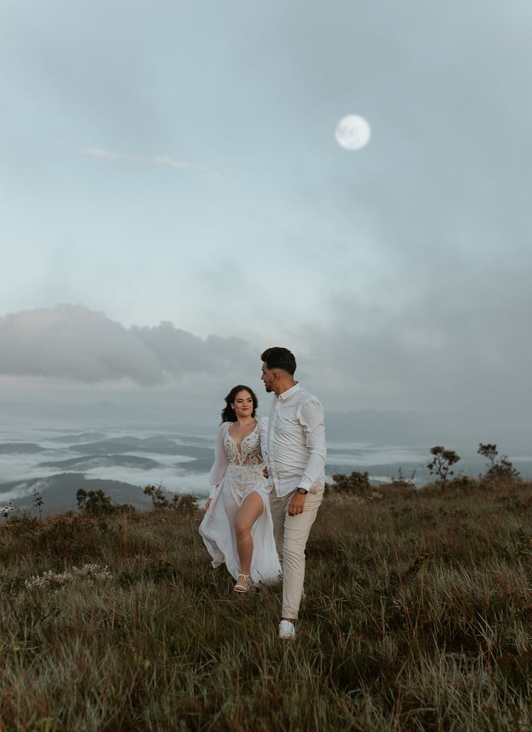 Young Couple Walking Together On Top Of A Grassy Hill