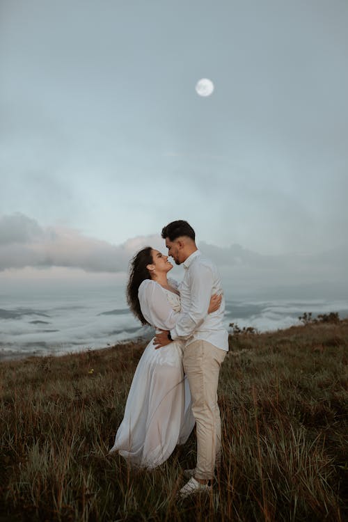 Young Couple Embracing on Top of a Grassy Hill