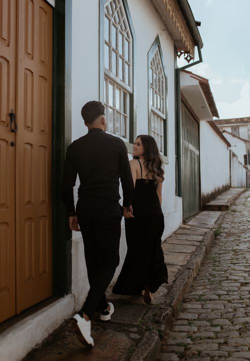 Free Couple walking hand in hand along a cobblestone street, exuding love and style. Stock Photo