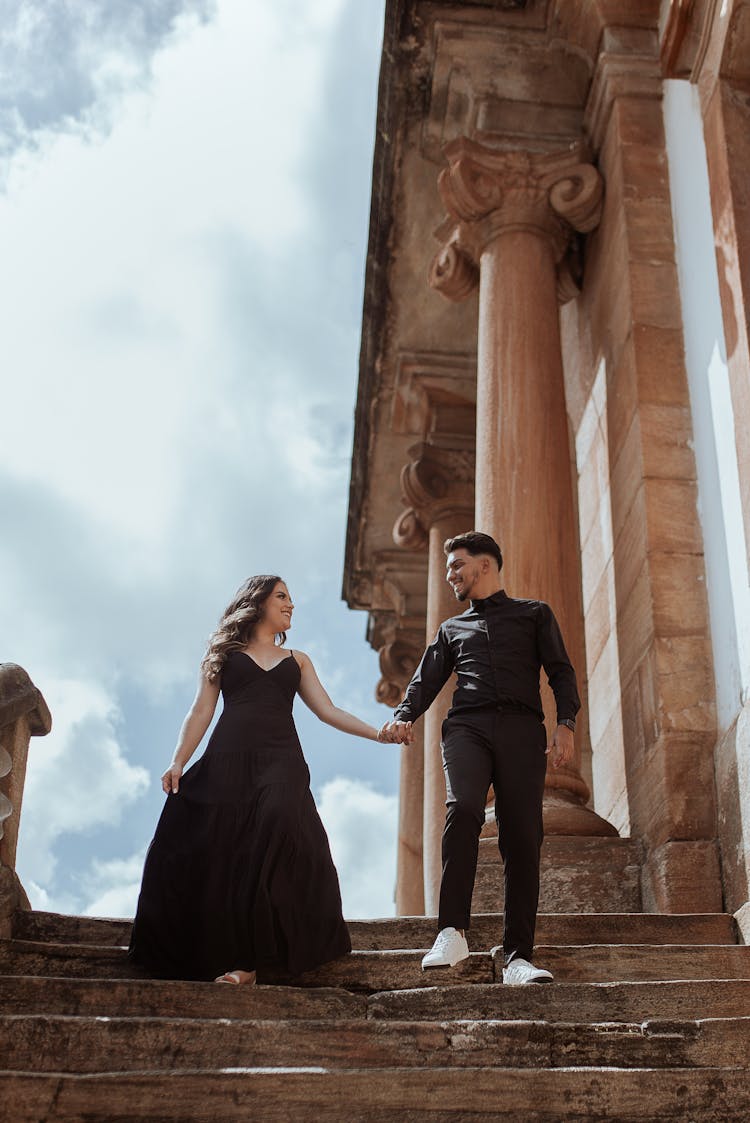 Well-Dressed Couple Holding Hands While Walking Down Stone Steps