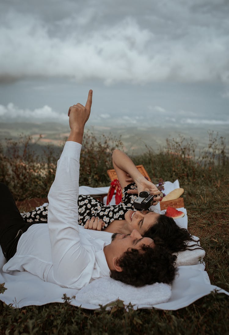 Smiling Couple Lying On Grass Enjoying Picnic In Nature