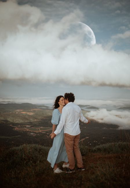 A couple shares a romantic moment dancing on a misty mountain with a dramatic moonlit sky.