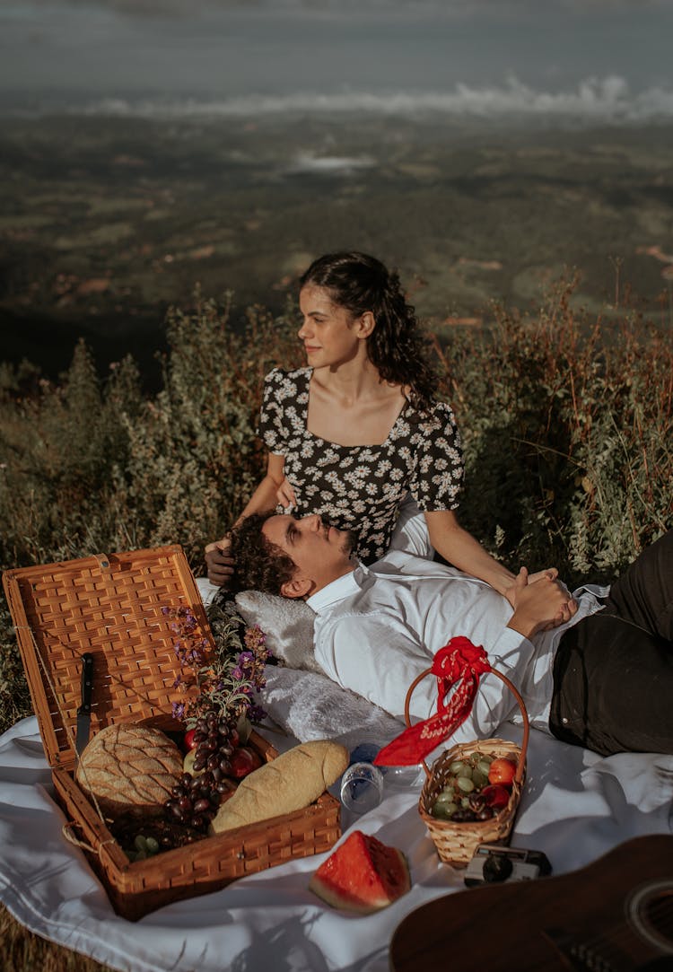 Couple Sitting On Grass Enjoying Picnic In Nature