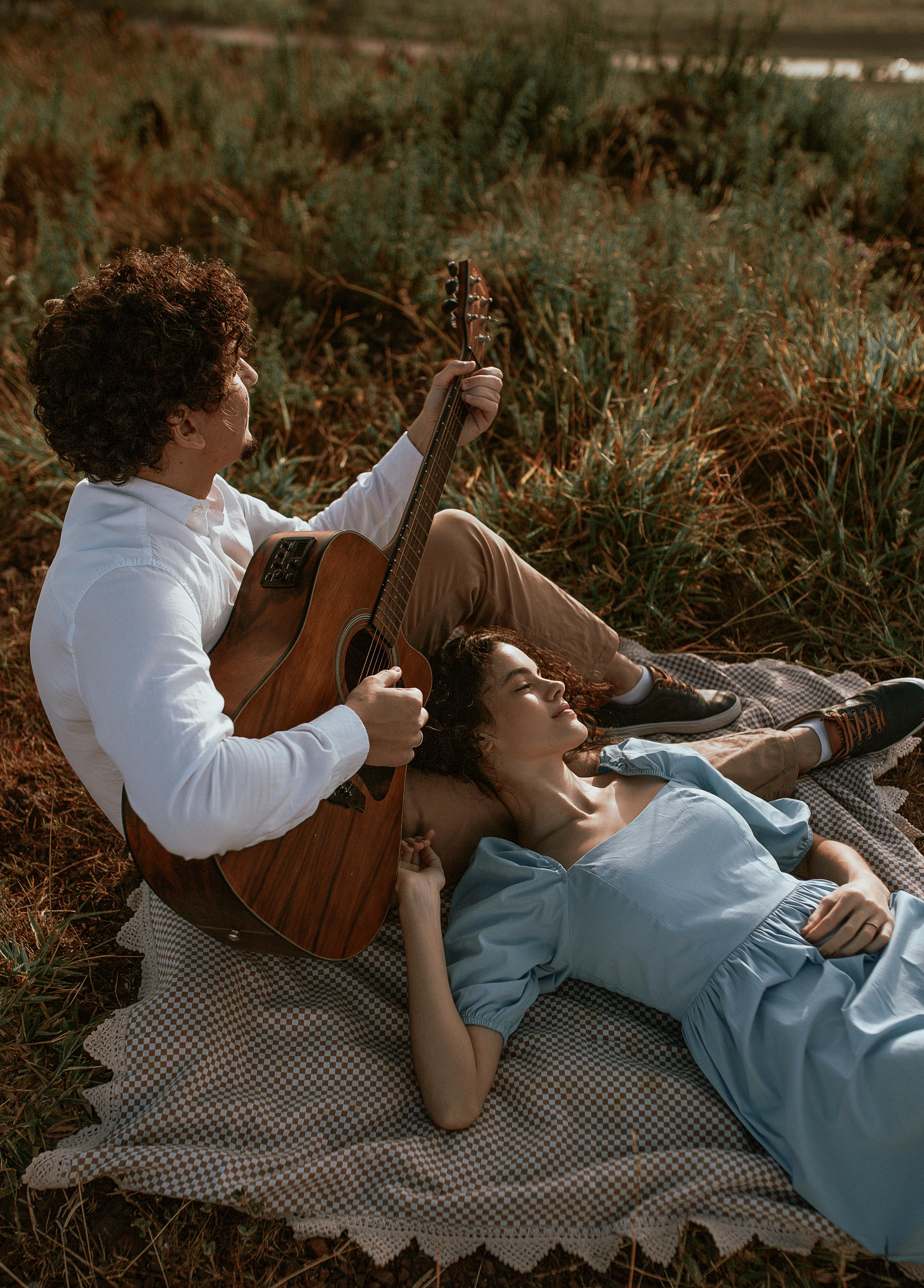 couple lying on the ground and man playing the guitar