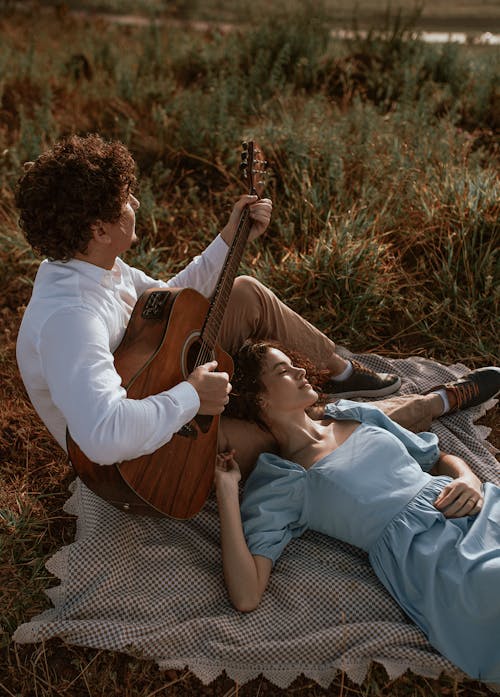 Couple Lying on the Ground and Man Playing the Guitar